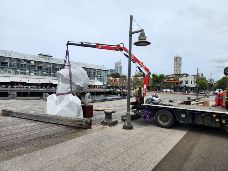 Wrapped sculpture being craned into position at a waterfront site